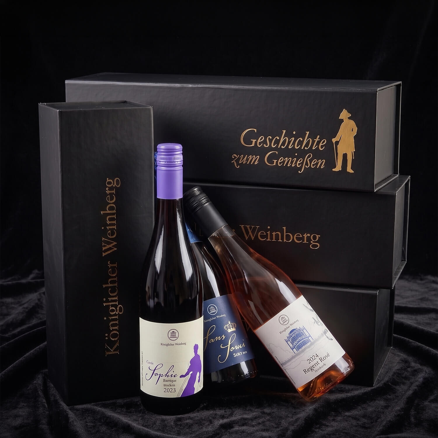 Drei Weinflaschen mit Wein aus Potsdam lehnen an schwarzen Geschenkkartons mit goldenen Schriftzügen. Hinweis: das Bild wurde mit KI optimiert.