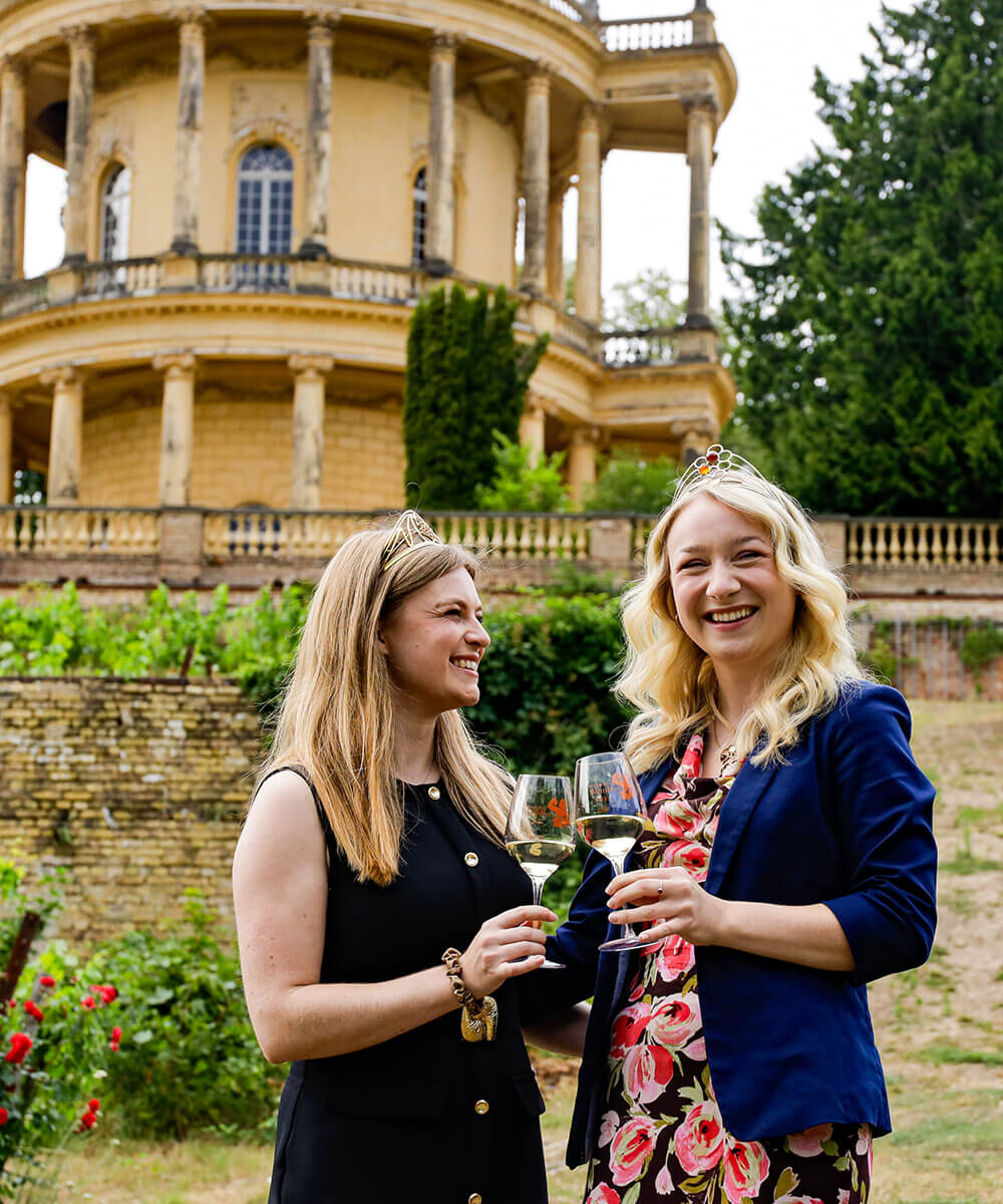 Zwei Weinköniginnen stoßen auf dem Königlichen Weinberg zusammen mit Weißwein an