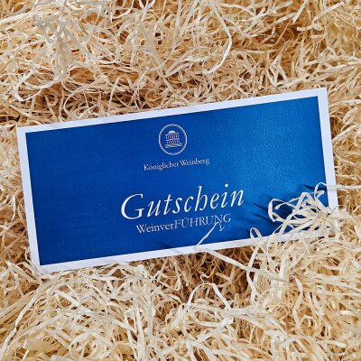 Gutschein aus Papier liegt auf einem Haufen Holzwolle